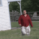 a man in a red shirt is running in a grassy field
