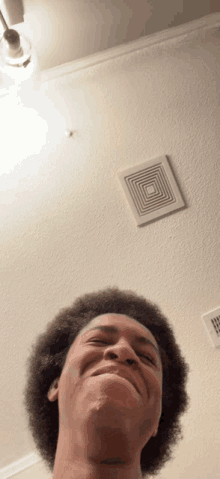 a man with an afro is smiling in front of a ceiling fan