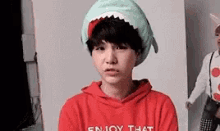 a young boy wearing a shark hat and a red shirt .