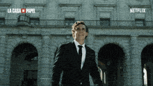a man in a suit stands in front of a building that says netflix