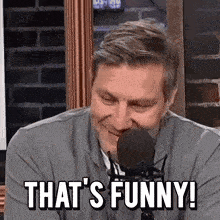 a man in front of a microphone with the words that 's funny on his face