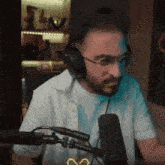 a man wearing headphones and glasses is talking into a microphone .