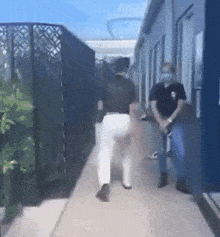 two people walking down a hallway one wearing a mask