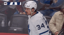 a hockey player with the number 34 on his jersey stands in the stands