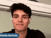 a young man wearing ear buds looks at the camera with the name mattia bottolo above him