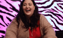 a woman is laughing in front of a pink and black zebra print .