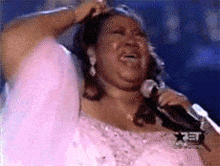 a woman in a pink dress is singing into a microphone ..