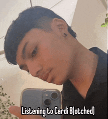 a young man taking a selfie with the caption listening to cardi b ( otched )