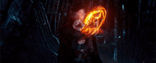 a man in a black cape is holding a circle of fire in his hand