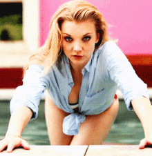 a woman in a blue shirt is kneeling on a pool edge
