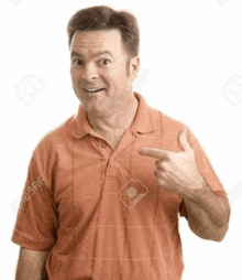 a man in an orange shirt is pointing at himself with his finger