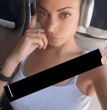 a woman wearing headphones is taking a selfie with a black stripe covering her armpit