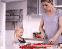 a woman and a little girl are preparing food in the kitchen .