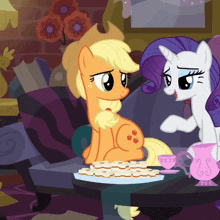 applejack and rarity are sitting at a table with cookies