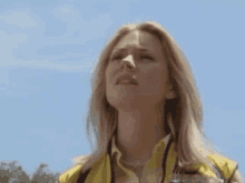 a woman wearing a yellow vest is looking down at something .