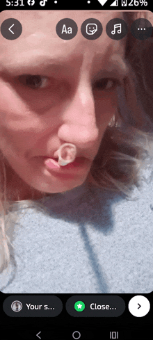 a close up of a woman 's face on a phone with a sticker in her nose