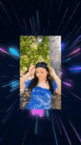 a woman in a blue dress is standing in front of a tree and trees