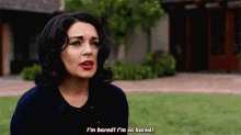 a woman is standing in front of a house and saying i 'm bored i 'm so bored
