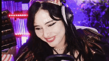a woman wearing headphones and a crown is smiling while playing a video game
