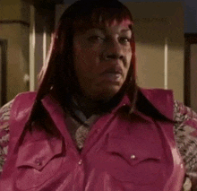 a woman with red hair is wearing a pink vest .