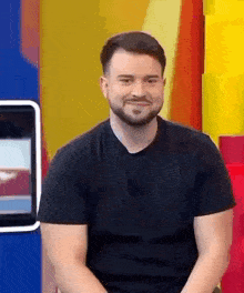 a man with a beard is sitting in front of a colorful wall .