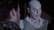 a man with a chain mail vest looks at another man
