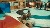 a person in a costume is driving a small toy car on a track .