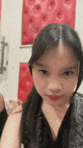 a close up of a young girl 's face with a red wall in the background
