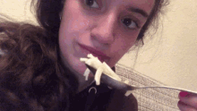 a woman with red nails is holding a spoon with a piece of food in her mouth .