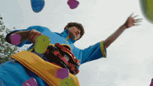 a man in a blue shirt is playing with balloons and a toy car