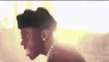 a man wearing a hat and a pearl necklace is standing in the sunlight .