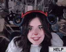 a woman wearing headphones and a clown makeup smiles in front of a help button