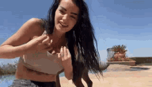 a woman in a crop top is playing with a dog in a pool .