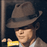 a man wearing a fedora hat and a suit is standing in front of a wall .