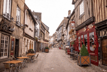 a narrow street with tables and chairs in front of a red building that says ' evelyn ' on it