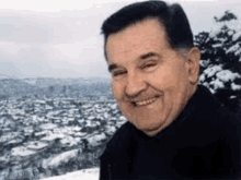 a man is smiling in front of a snow covered city .