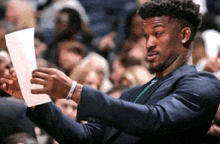 a man in a suit is holding a piece of paper in his hand