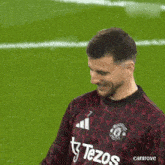 a man wearing a shirt that says tizos is smiling