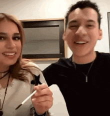 a man and a woman are posing for a picture while the man is holding a pen .