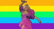 a woman in a pink dress is holding a microphone in front of a rainbow background .