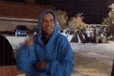 a man in a blue hoodie is smiling in a parking lot .