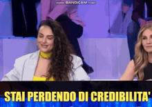 two women are sitting in front of a screen that says stai perdendo di credibilita
