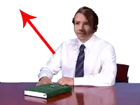 a man in a white shirt and tie sits at a desk with a book on it