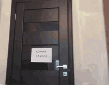 a black door has a sign on it that says kommata ta roca