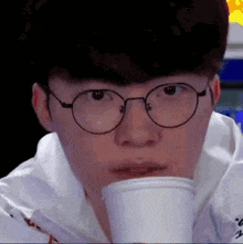 a close up of a person wearing glasses drinking from a cup .