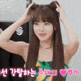 a woman in a green and yellow dress is holding her hair in pigtails
