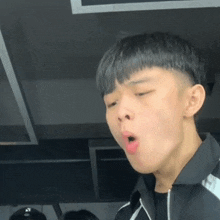a young man in a black jacket is making a funny face with his mouth open .