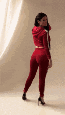 a woman in a red tracksuit is standing in front of a curtain