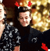 a man wearing a reindeer headband is standing next to a woman wearing a santa hat .