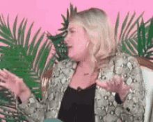a woman in a snake print jacket is sitting in a chair talking to someone .